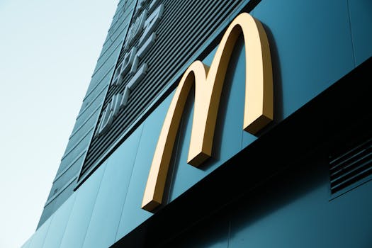 Large fast food restaurant golden arch sign on a modern building facade.